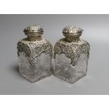 A pair of late Victorian repousse silver mounted cut glass scent bottles with stoppers, William