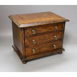 A cross banded walnut miniature chest of three drawers, 26cm wide