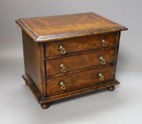 A cross banded walnut miniature chest of three drawers, 26cm wide