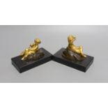 A pair of ormolu putto paperweights on black marble bases,13 cms wide.