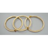 Three gilt white metal and cultured pearl set bangles.