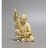 A Japanese ivory okimono of seated figure, early 20th century (possibly Gama Sennin) with paddle and
