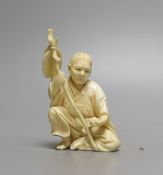 A Japanese ivory okimono of seated figure, early 20th century (possibly Gama Sennin) with paddle and