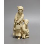 A Japanese ivory okimono of a crouching man and a woman holding a flower basket, Meiji period,