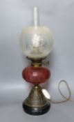 An Edwardian oil lamp with ruby glass font, later inverted to electricity,57 cms high including