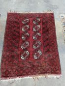 An Afghan red ground rug, woven with two rows of elephant feet, 130 x 100cm