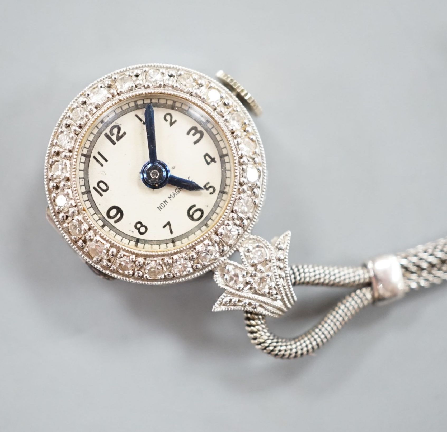 A lady's 1920's white metal (stamped platinum) and diamond chip set lapel watch, 6cm, gross weight