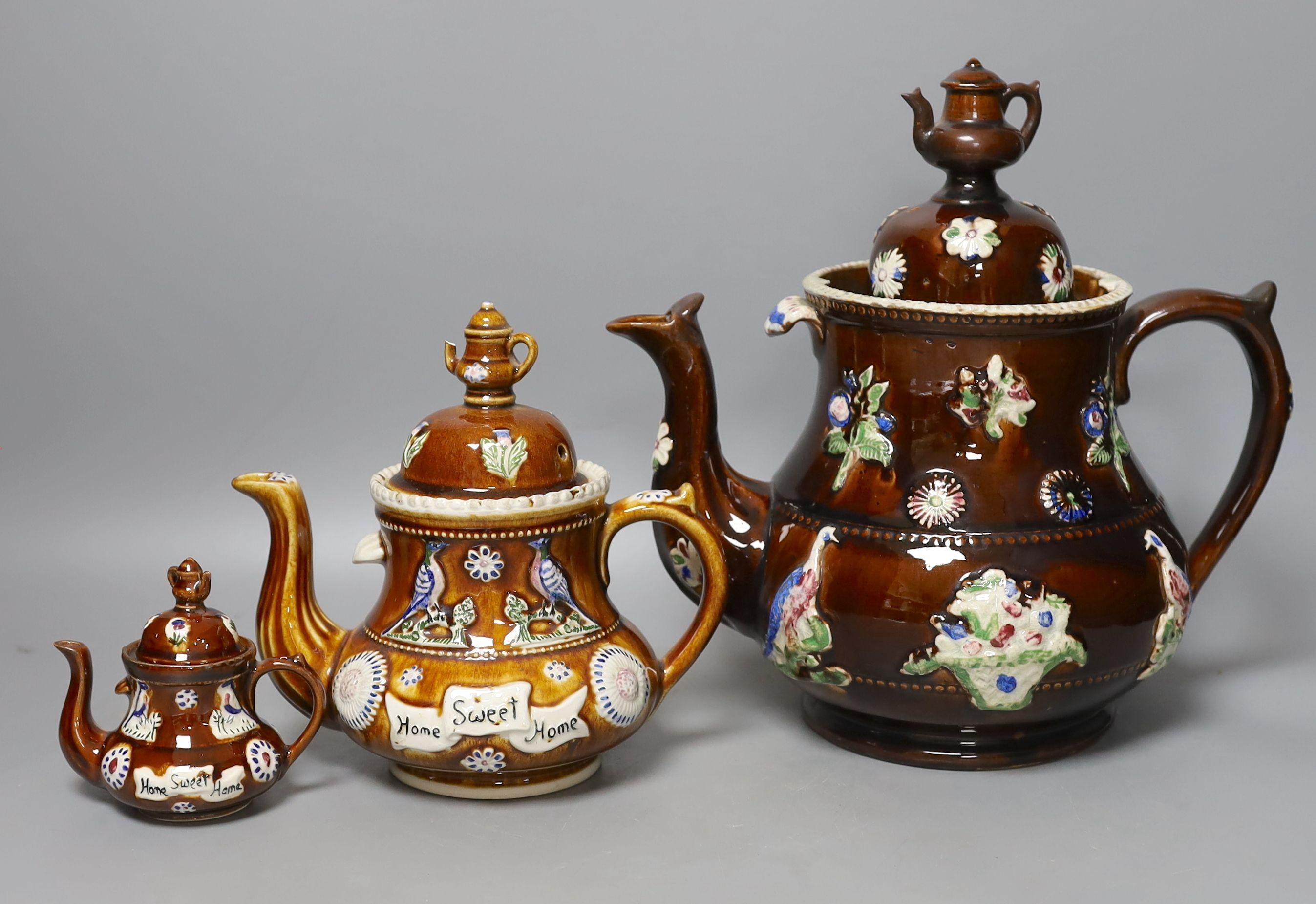 A Measham Bargeware pottery tea pot and cover and two similar reproductions