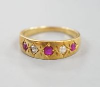An early 20th century yellow metal and gypsy set three ruby and two stone diamond ring, size P,
