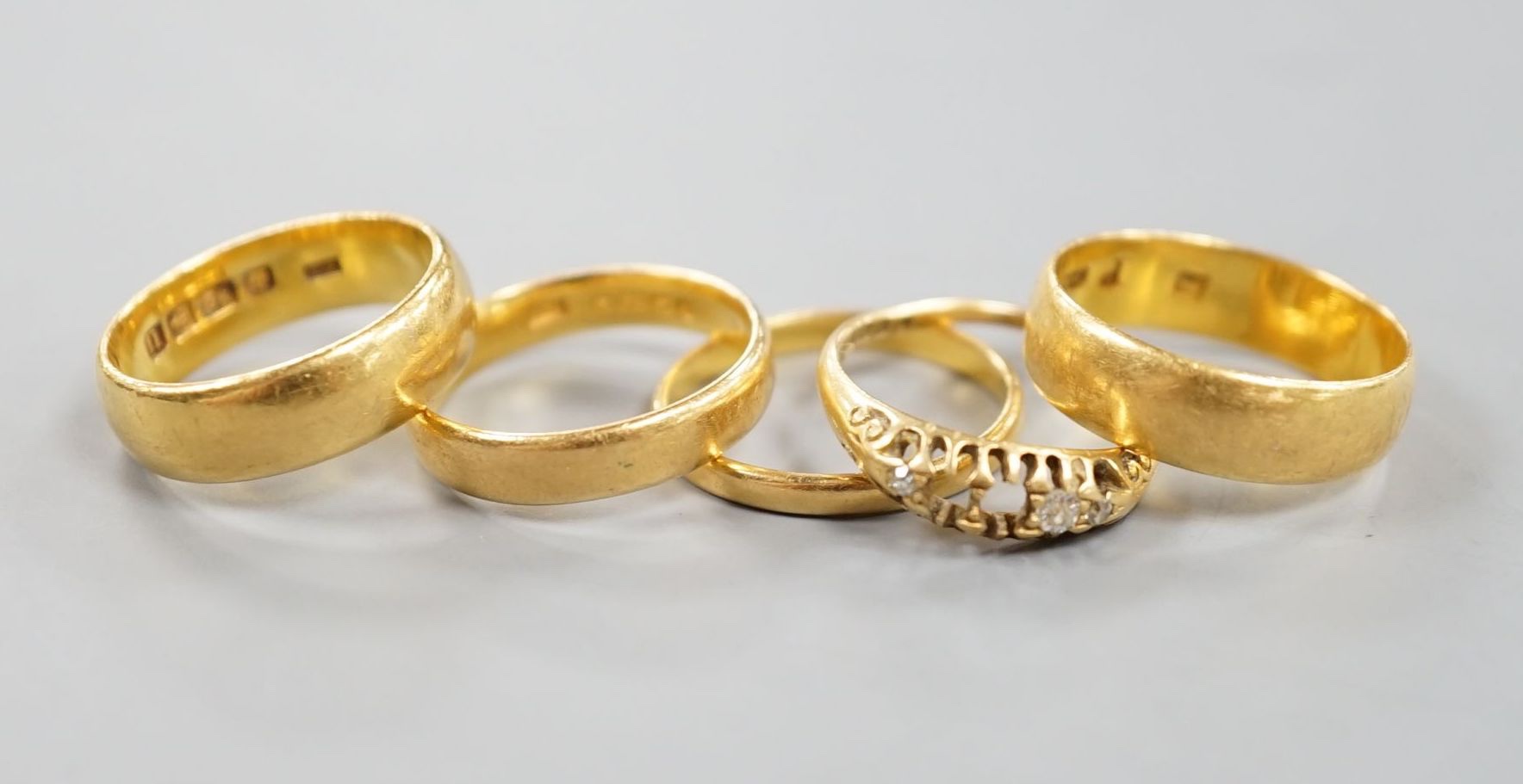 Four assorted mainly early 20th century 22ct gold wedding bands and an 18ct and diamond chip set