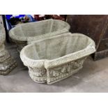 A pair of shaped oval reconstituted stone garden planters with floral swag bodies, width 82cm, depth