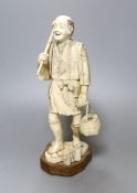 An carved and engraved ivory figure of a labourer, Meiji-period, on plinth, 25cm