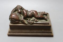 A bronze recumbent putti on wooden base