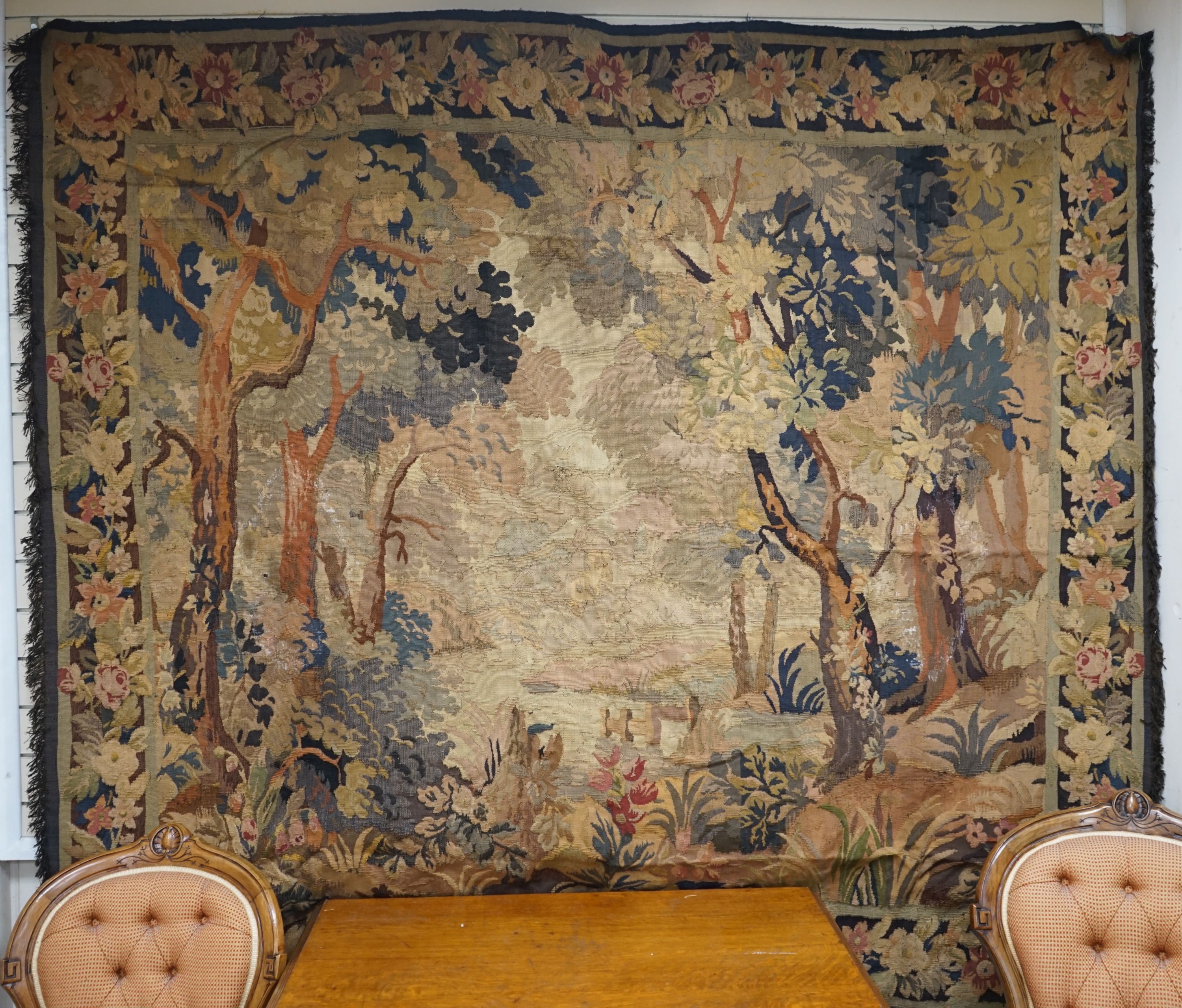 A late 19th / early 20th century French tapestry depicting a woodland scene with trees and flowers