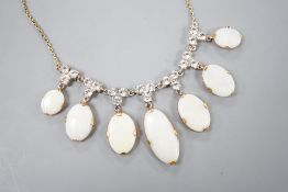 A yellow metal, graduated seven stone oval white opal and paste set cluster fringe necklace, 42cm,