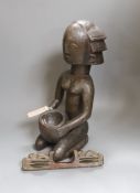 An African tribal carved wood kneeling figure holding bowl (44cm high) and tribal hand instrument (