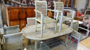 A weathered teak extending oval garden table, length 196cm, width 110cm, height 75cm and eight