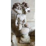 A reconstituted stone seated cherub and orb garden ornament, height 84cm