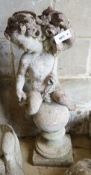 A reconstituted stone seated cherub and orb garden ornament, height 84cm