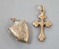 A 9ct gold cross pendant charm, 21mm and a similar engraved yellow metal shield shaped locket