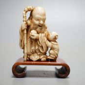 A Japanese ivory netsuke of Hotei and a boy, Meiji period, signed,5 cms high.