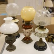 A Doulton style pottery oil lamp and four other glass and brass oil lamps, tallest 54 cms