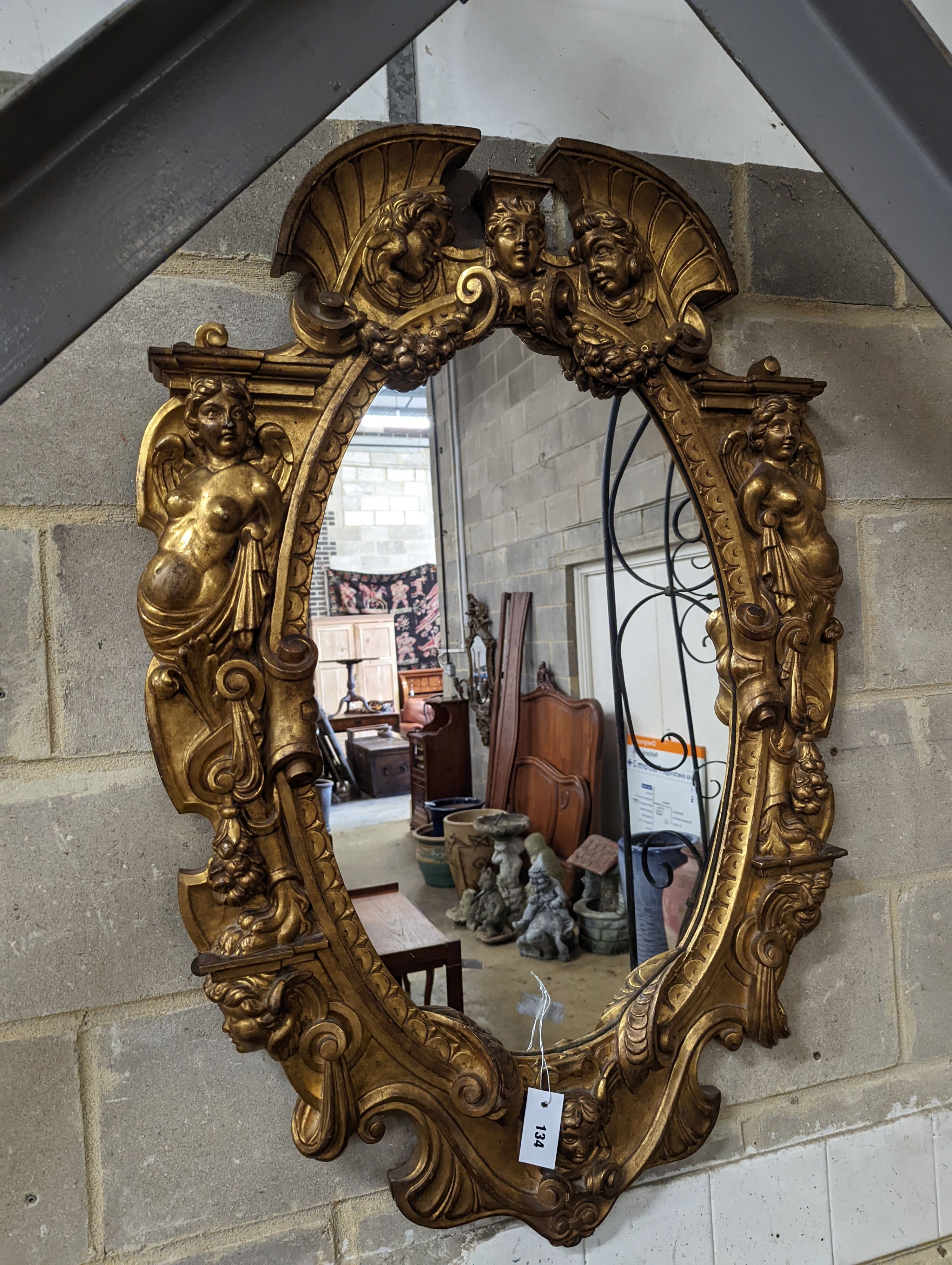 A Victorian carved giltwood oval wall mirror decorated with cherubs and C scrolls., width 74cm,