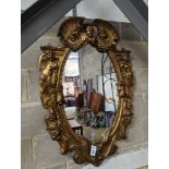 A Victorian carved giltwood oval wall mirror decorated with cherubs and C scrolls., width 74cm,