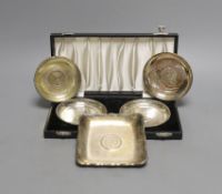 A cased pair of white metal inset coin small dishes and three other similar dishes.