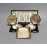 A cased pair of white metal inset coin small dishes and three other similar dishes.