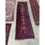 A Belouch red ground runner, 274 x 77cm