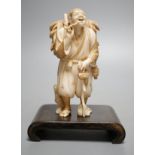 A Japanese ivory figure of a farmer smoking a pipe, Meiji period, signed - 12cm tall