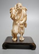 A Japanese ivory figure of a farmer smoking a pipe, Meiji period, signed - 12cm tall