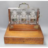 A three decanter tantalus - with labels, together with an oak canteen of table plated cutlery