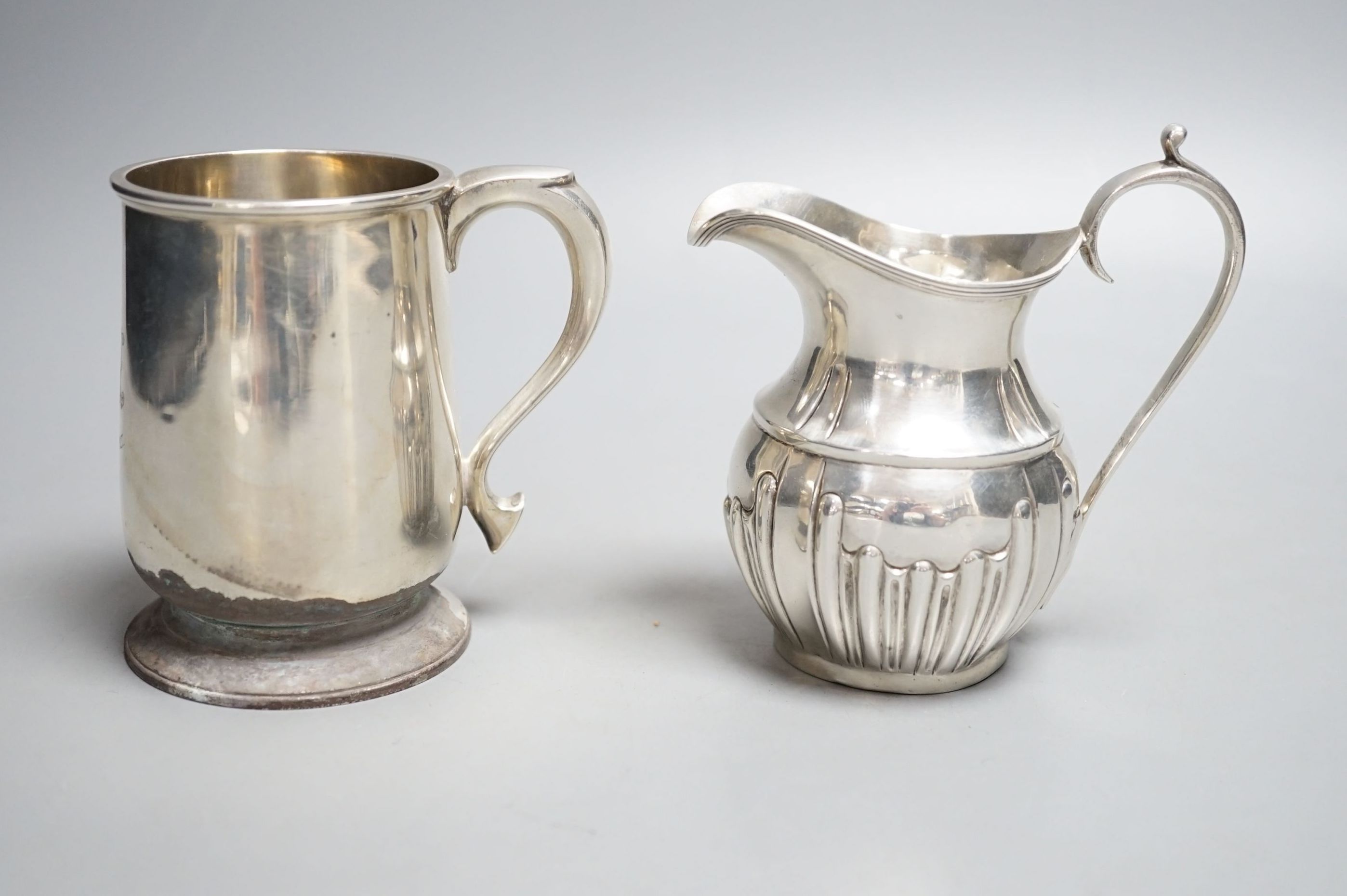 A late Victorian silver cream jug, Nathan & Hayes, Chester, 1897 and a George V silver christening