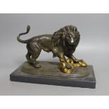 A patinated spelter figure of a lion slaying a serpent on mounted base - 24cm long