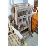 Four weathered teak folding garden chairs, a pair of teak reclining elbow chairs and a pair of