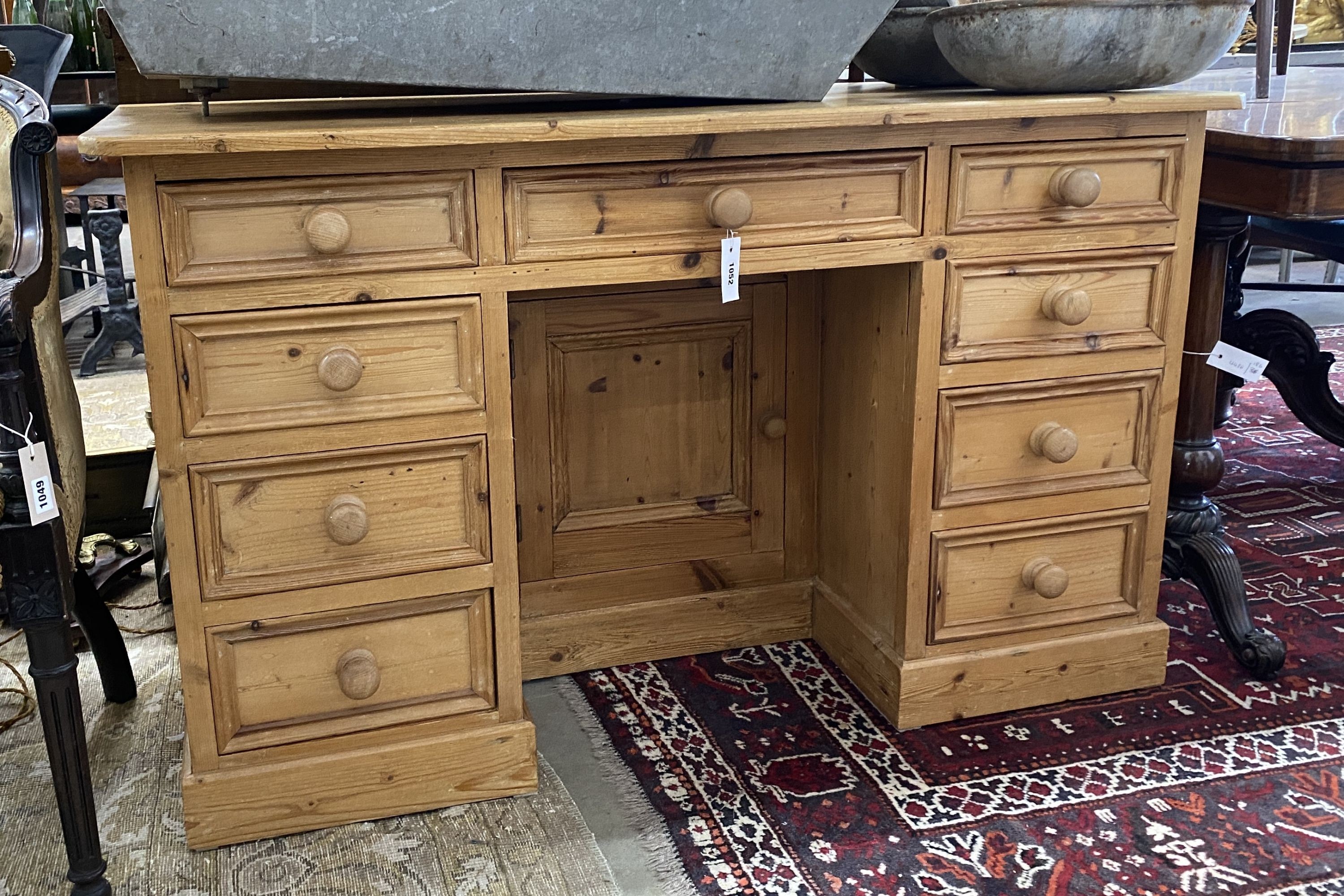 A Victorian style pine kneehole nine drawer desk with recessed cupboard, length 130cm, depth 50cm,