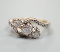 A yellow metal and three stone diamond set crossover ring, with diamond set shoulders, size I, gross