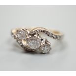 A yellow metal and three stone diamond set crossover ring, with diamond set shoulders, size I, gross