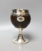 An early 19th century white metal mounted coconut cup, on pedestal stem, unmarked, height 15.6cm,
