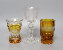 Two Bohemian wheel engraved amber flashed beakers, one with titled topographical views and a wheel