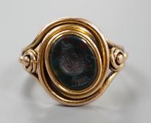 A Victorian yellow metal and oval bloodstone set signet ring, the matrix carved with family crest,