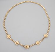 A late Victorian yellow metal and seed pearl set flower head motif necklace, (lacking drop pendant),