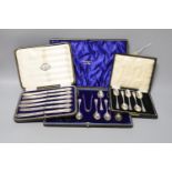 A cased set of twelve Edwardian silver teaspoons with tongs, a cased set of six tea knives and a