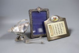 A George V silver sugar basket, a pair of sugar tongs, a silver photograph frame and a silver framed