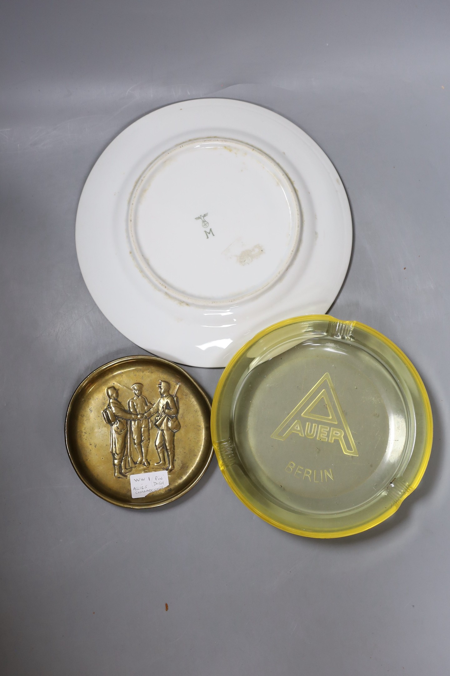 A WWII German Mess Hall porcelain plate, an Auer Berlin yellow glass ash tray and a WWI trench art