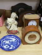A tin mantel clock and 3 wooden clocks, 2 dog door stops and a blue and white plate.
