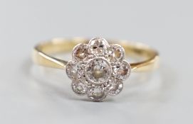 An 18ct and nine stone diamond set flower head cluster ring, size O, gross weight 2 grams.