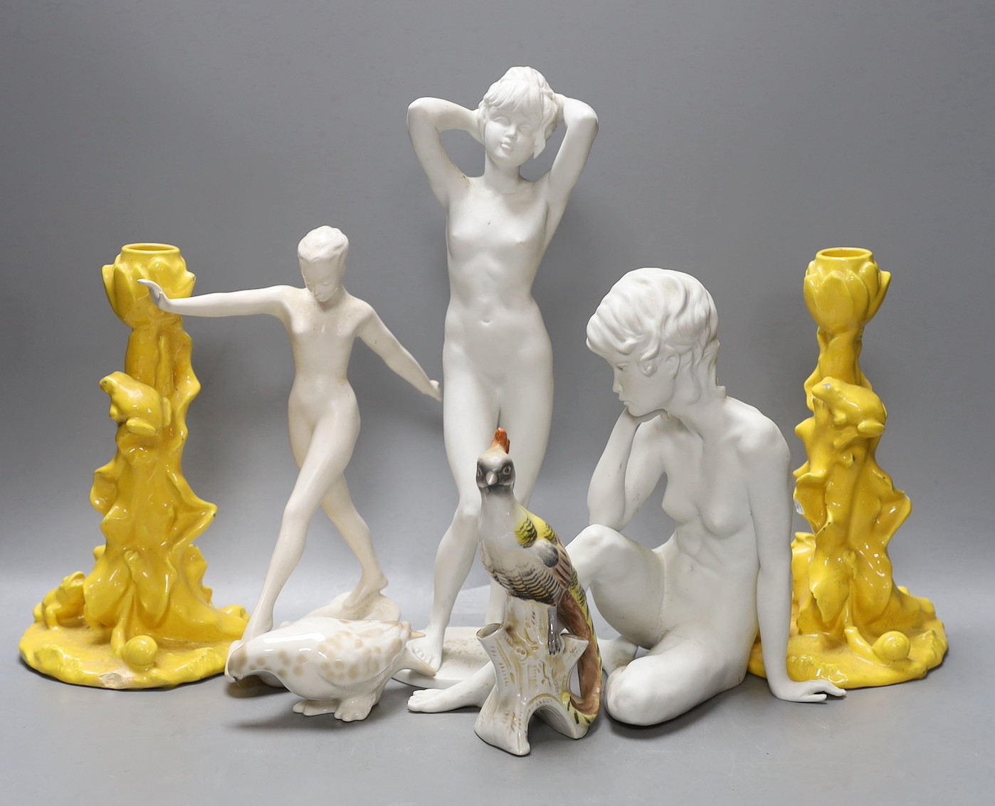 Two Kaiser porcelain figures, a Goebel figure, a pair of yellow glazed candlesticks with frogs and